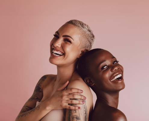 Front view of two women with short hair standing back to back