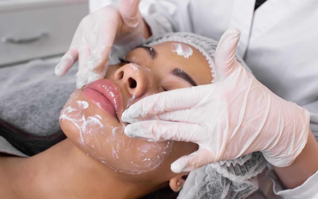 Image of a professional applying a facial cleanser on their client.