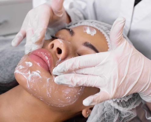 Image of a professional applying a facial cleanser on their client.