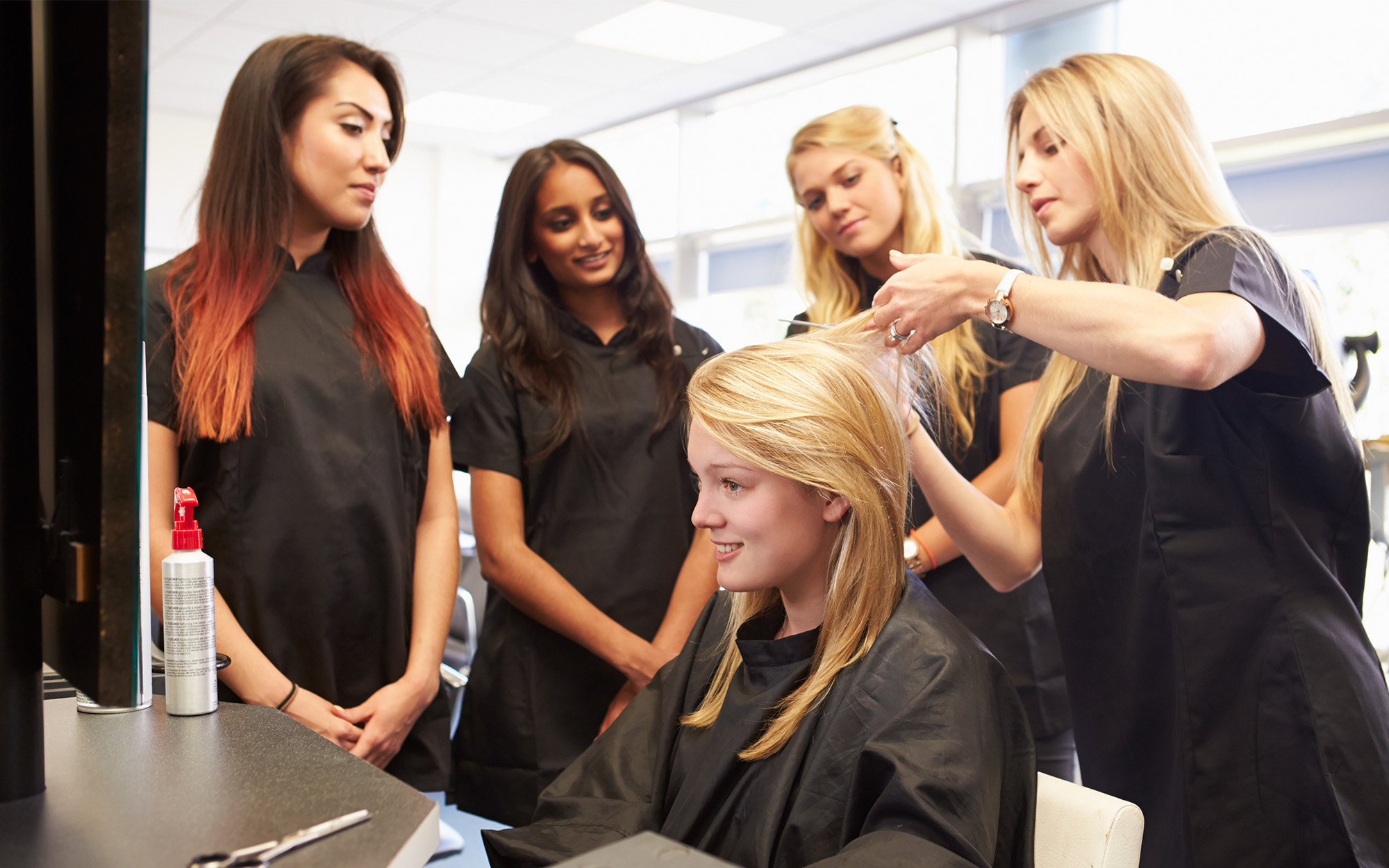 Teacher Helping Students Training To Become Hairdressers