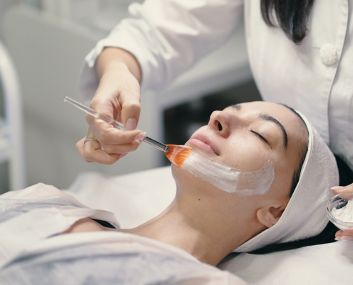 Person In White Robe Getting Esthetics Face Mask